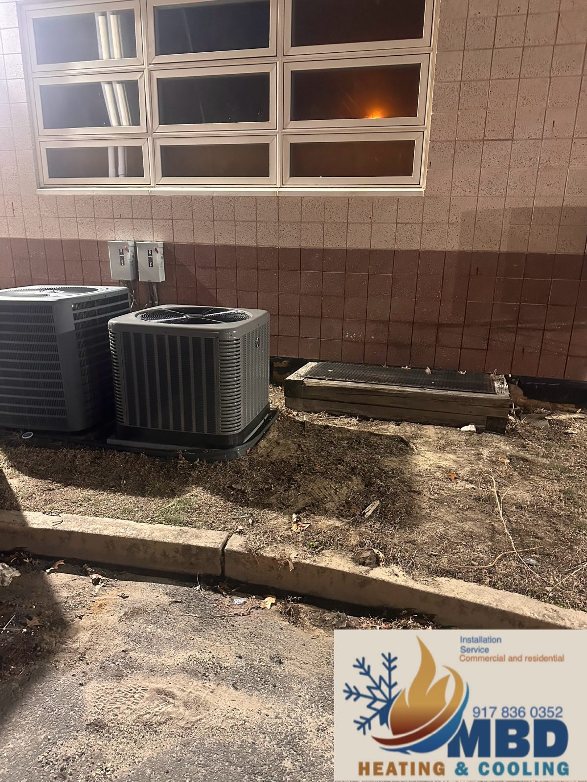Two outdoor condensers against a brick wall