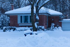 Single-story brick home covered in deep snow during a cold winter