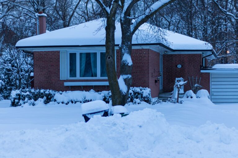 Single-story brick home covered in deep snow during a cold winter