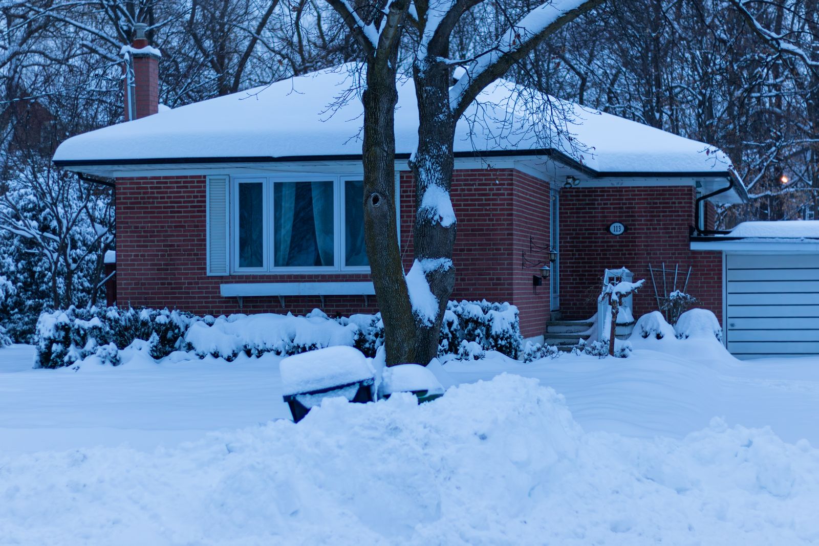 Single-story brick home covered in deep snow during a cold winter