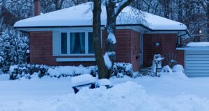 Single-story brick home covered in deep snow during a cold winter